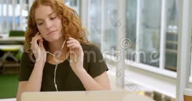 女商人在书桌旁听手机音乐